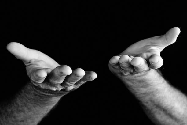 istock Masculine hands held palm up, giving support, against black 678502338