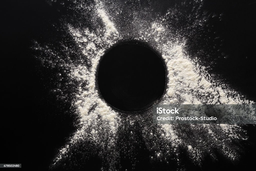 Baking concept on black background, sprinkled flour circle with copy space Abstract background. Sprinkled wheat flour circle, round spot on black. Top view on blackboard. Baking concept, cooking dough or pastry. Flour Stock Photo