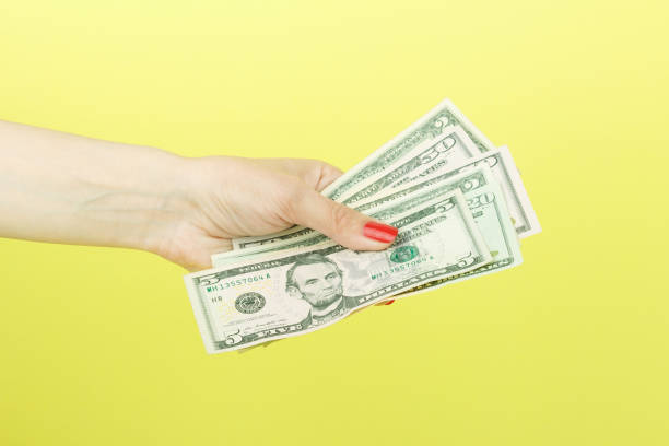 istock American dollars in the woman's hand, yellow background 678502528