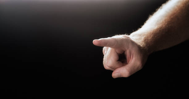 istock Masculine hand pointing diagonally toward camera against black 678502700