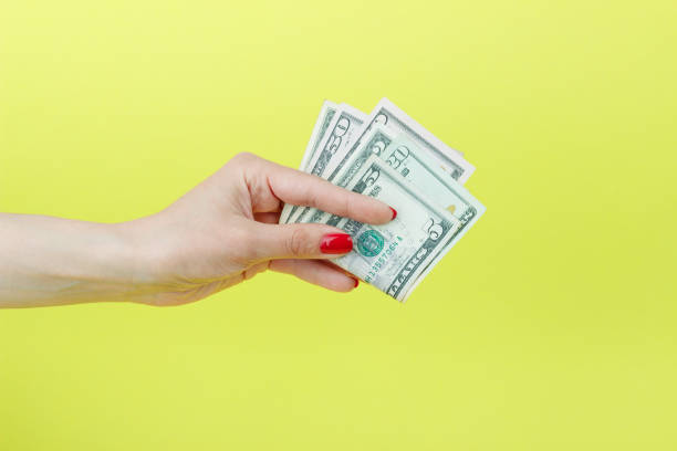 istock American dollars in the woman's hand, yellow background 678507474