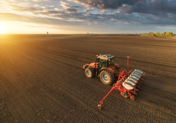 Farmer with tractor seeding - sowing crops at agricultural fields in spring Farmer with tractor seeding - sowing crops at agricultural fields in spring agricultural machinery stock pictures, royalty-free photos & images