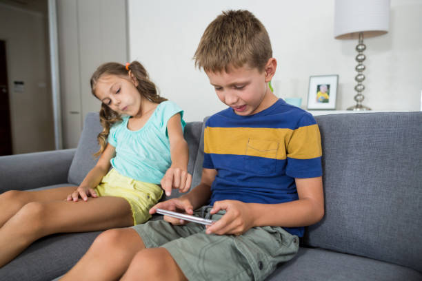 istock Smiling siblings using digital tablet on sofa in living room 678508996