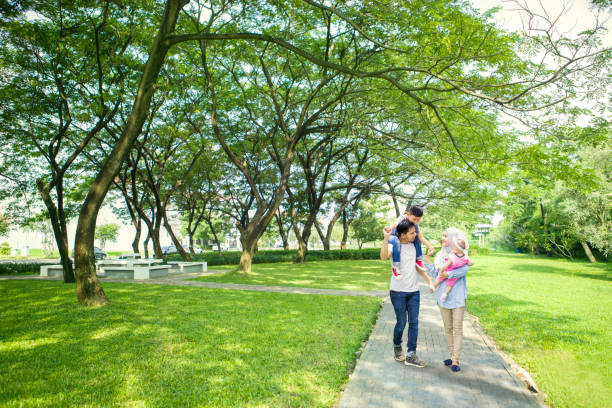 Muslim family spending time in the park Image of Muslim parents spending time with their children while walking in the park malay stock pictures, royalty-free photos & images