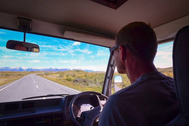 istock Man drives old camper van open road to snow-capped mountains 678514026