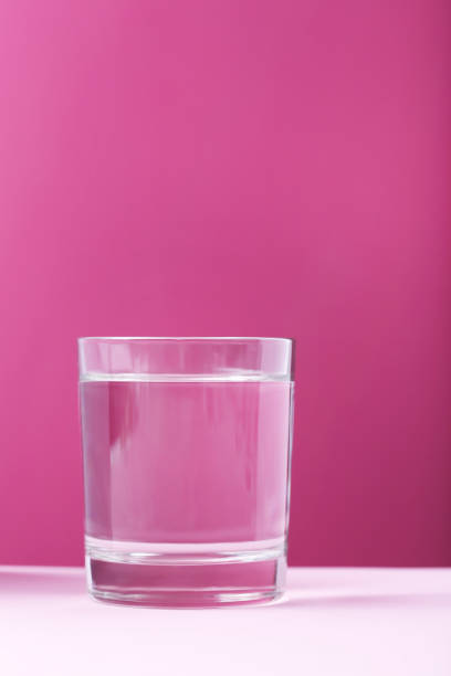 istock Glass with water on pink background 678536166
