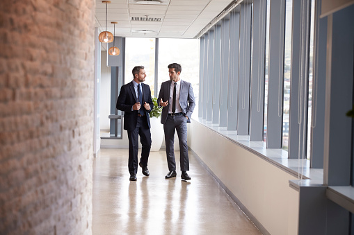 Two Businessmen Having Informal Meeting In Office Corridor