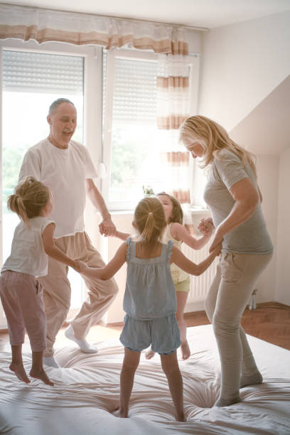 Grandmother and grandfather together with their granddaughters. Grandmother and grandfather together with their granddaughters dancing on the bed. sleeping grandpa stock pictures, royalty-free photos & images