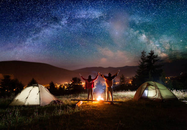 istock Night camping. Pair hikers stands and holding hands 678554888