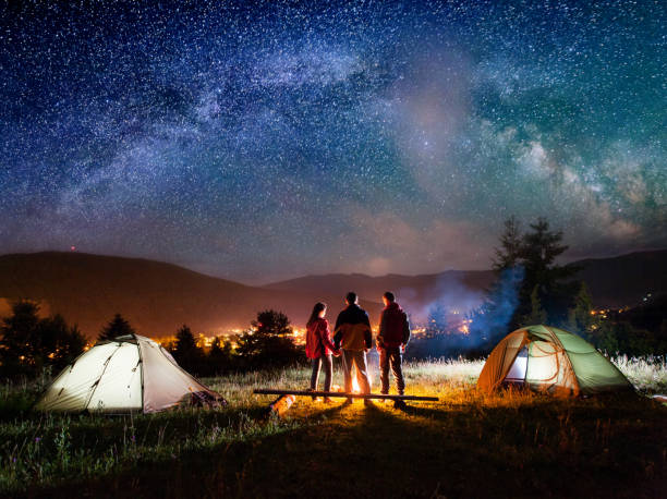 vista posteriore coppia escursionisti in piedi vicino falò in campeggio - friendship camping night campfire foto e immagini stock