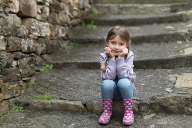 Little girl sitting on the stairs on rainy day