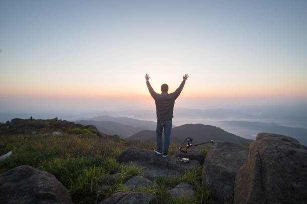 istock man standing on rock with photography kit 678557446