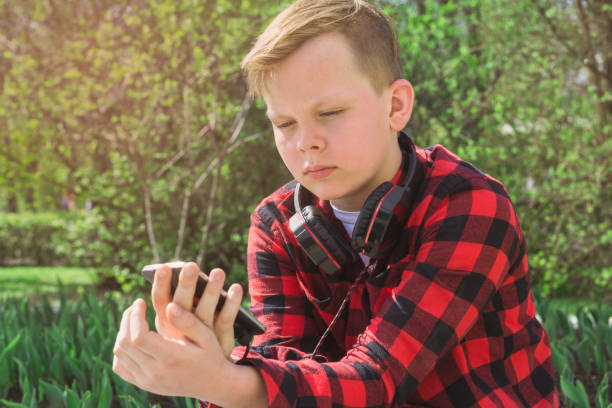istock Handsome teenager surfing the net while sitting in park. 678583872