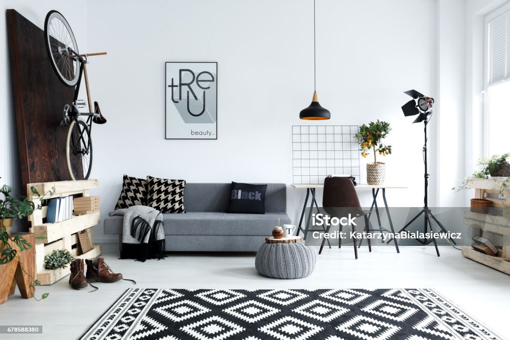 White living room with sofa Hipster style, white living room with sofa, pouf, carpet, bike Black And White Stock Photo
