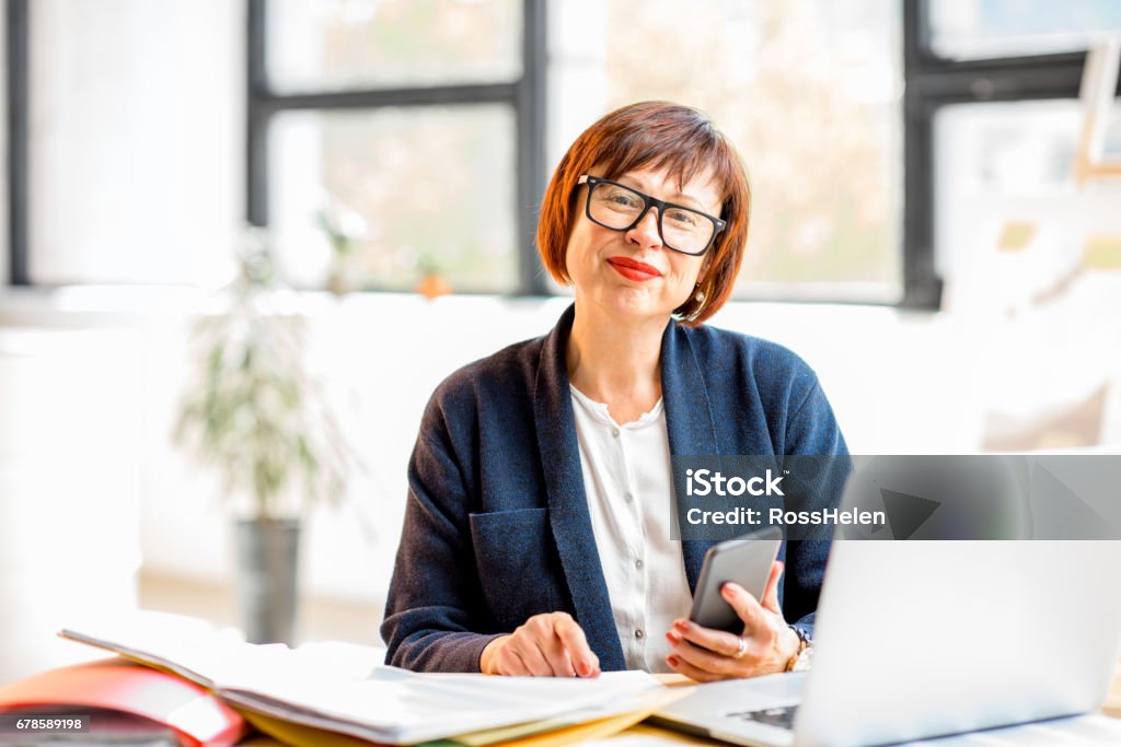 Imprenditrice senior in ufficio - Foto stock royalty-free di Luce vivida