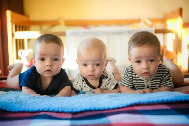 Portrait of newborn triplets are lying in the bed