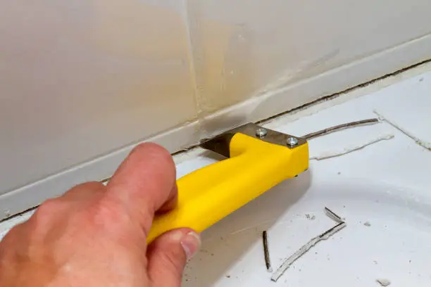 Man remvoe a old silicone joint in a shower