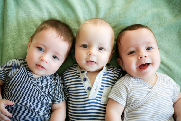 Portrait of newborn triplets are lying in the bed Portrait of newborn triplets are lying in the bed group of babies stock pictures, royalty-free photos & images