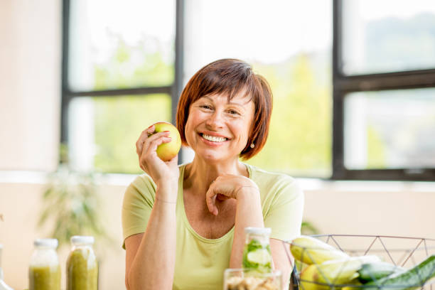 starsza kobieta ze zdrową żywnością w pomieszczeniach - apple healthy eating healthy lifestyle healthcare and medicine zdjęcia i obrazy z banku zdjęć