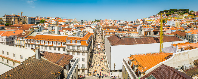 Panoramic blue skies above the terracotta rooftops and crowded streets of the Baixa shopping district overlooked by the battlements of Castelo de Sao Jorge in the heart of Lisbon, Portugal’s vibrant capital city.