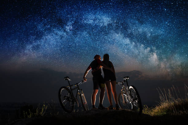 istock Couple cyclists with mountain bikes at night under starry sky 678627010
