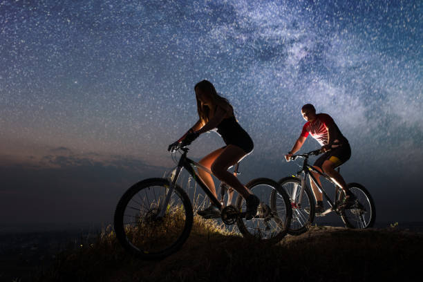 istock Sporty couple riding a bicycles at night under starry sky 678627014