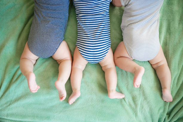 trigêmeos recém-nascidos deitam de barriga para cima de um cobertor - baby cheerful child blanket - fotografias e filmes do acervo