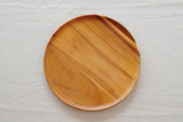 istock Empty round wooden plate on linen table cloth, food background, display montage 678645290