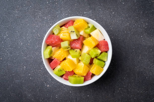 Colorful fruit salad on gray stone table.