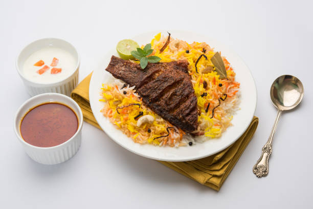 poisson biryani ou riz de poisson - recette indienne populaire non végétarienne faite de poisson mariné aux épices indiennes herbes fraîches et cuit avec du riz basmati, objectif sélectif - nonvegetarian photos et images de collection