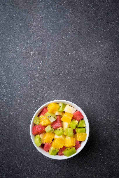 istock Colorful fruit salad on gray stone table. 678661368