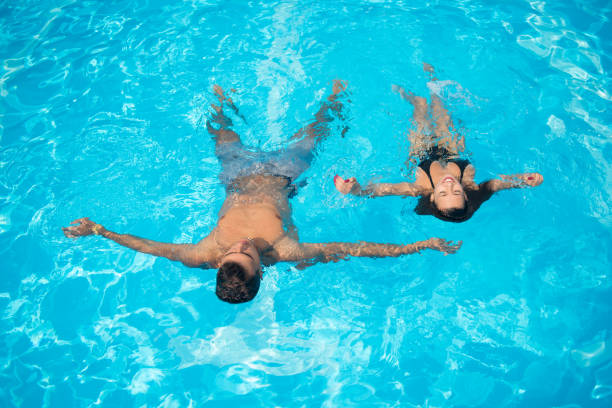 istock Couple floating on the surface in the swimming pool on the turquoise water at summer vacation 678679708