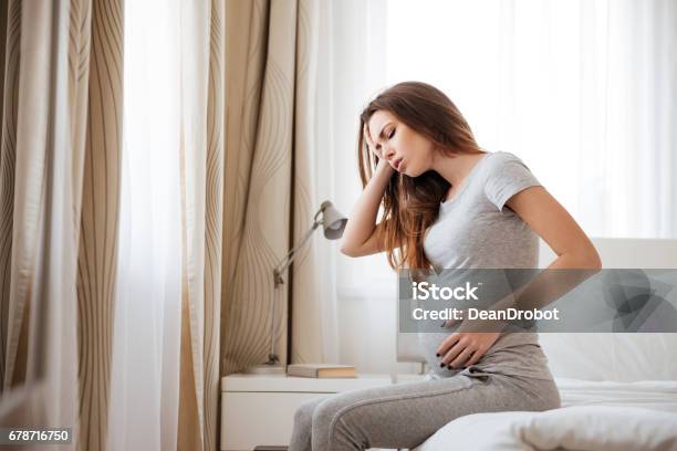 Sad Pregnant Woman Having Headache And Feeling Sick On Bed Stock Photo - Download Image Now