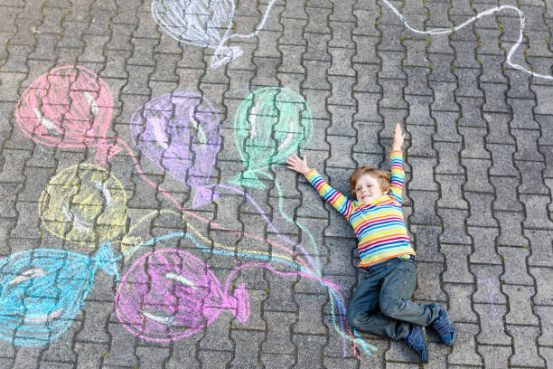 istock Kid boy having fun with colorful balloons drawing with chalks 678729078