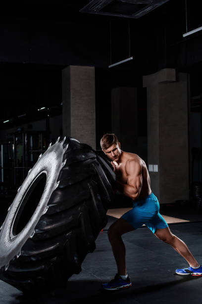 istock gym training - man flipping tire in gym 678744390