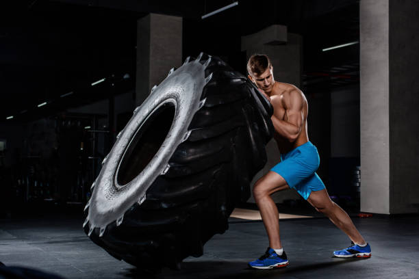 istock gym training - man flipping tire in gym 678744556