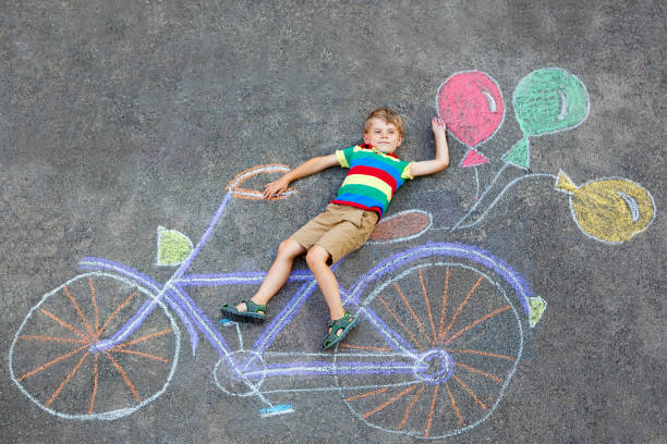 istock little kid boy having fun with bicycle chalks picture on ground 678748136