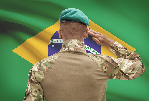 Dark-skinned soldier in hat facing national flag series - Brazil