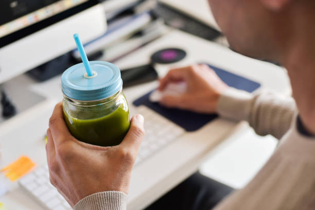 オフィスで緑のスムージーを飲む男 - beet green ストックフォトと画像