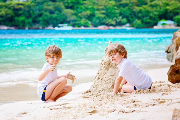 istock Two kid boys building sand castle on tropical beach 678757066
