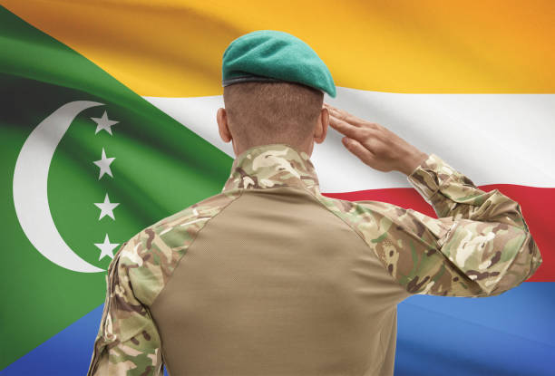 istock Dark-skinned soldier with flag on background - Comoros 678757740