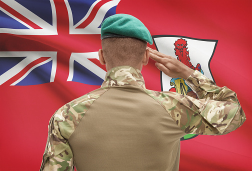 Dark-skinned soldier in hat facing national flag series - Bermuda