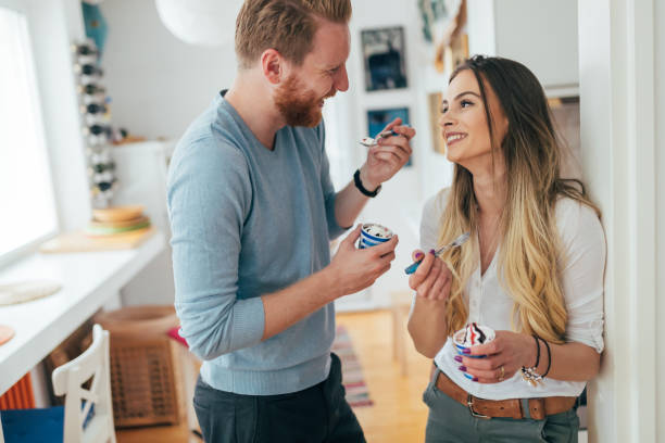 istock Beautiful couple having fun and laughing at home while eating ice cream 678780902