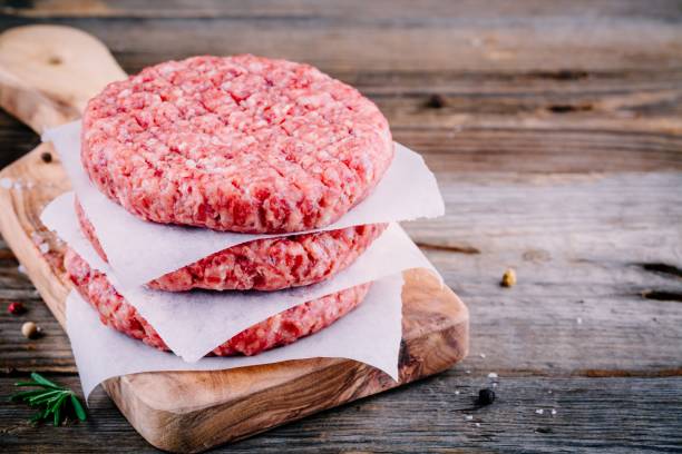 Ingredients for burgers: raw minced beef cutlets Ingredients for burgers: raw minced beef cutlets on wooden background pink pepper spice ingredient stock pictures, royalty-free photos & images