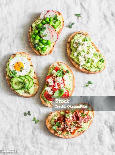 Variation Avocado Sandwich With Crispy Bacon Quail Egg Tomatoes Goat Cheese Green Peas Radish Cucumber Healthy Snack On A Light Background Top View Stock Photo - Download Image Now