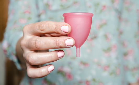 Cerca de la mano de la mujer sosteniendo la copa menstrual photo