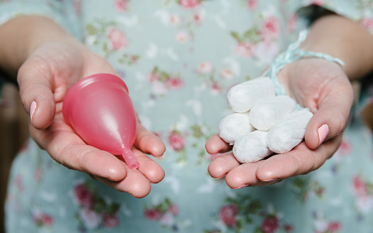 Mujer celebración de tampones y copa menstrual en manos photo