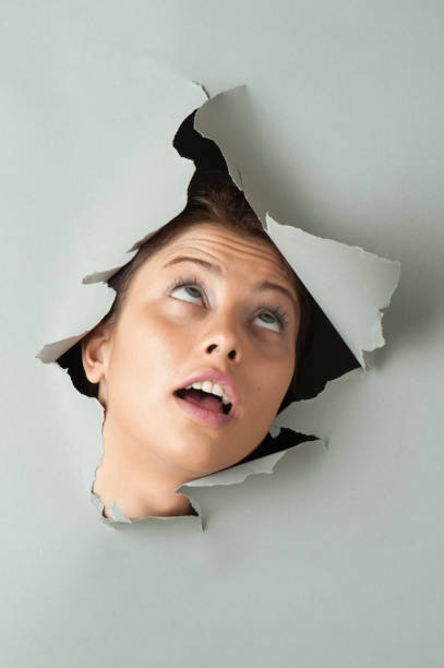 istock Woman looking through torn paper 678798740