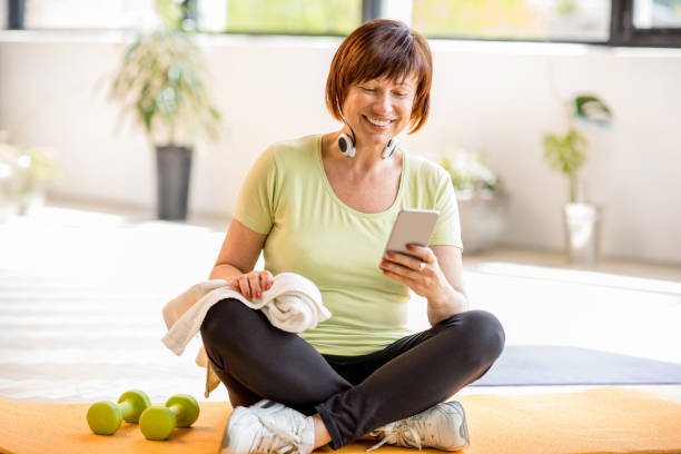 vielles femmes sportives avec le smartphone à l’intérieur - aging process audio photos et images de collection