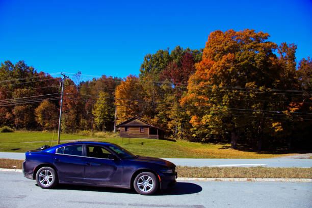 Dodge Charger parked beside house Mt Mansfield, Vermont, USA - 10/09/2015 : Taken this picture near Mt Mansfield of a sedan car Dodge Charger beside a house at the countryside. Taken this picture during fall time and tried to capture the changing color of landscape as well as a beautiful car in front. dodge charger stock pictures, royalty-free photos & images
